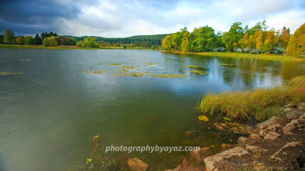 Autumn Lakeside with Cabins and Lily Pads – Fine Art Nature Photography  Photography by Ayaz